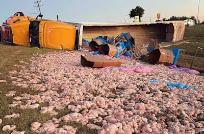 Overturned yellow vehicle with scattered cargo and debris on gravel ground at accident scene