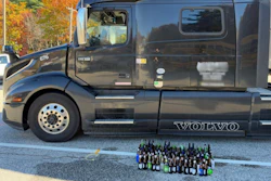 Black Volvo truck with collection of beer bottles displayed in front during autumn