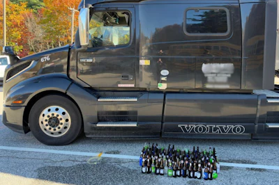 Black Volvo truck with collection of beer bottles displayed in front during autumn