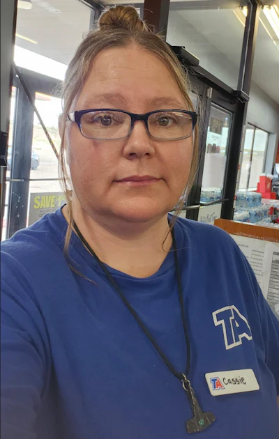 Woman wearing blue TA uniform with name badge in retail store setting